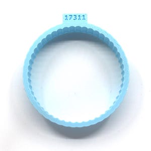 Puede incluir: Un cortador de galletas de silicona azul claro con un borde festoneado y el número "17311" impreso en la parte superior.