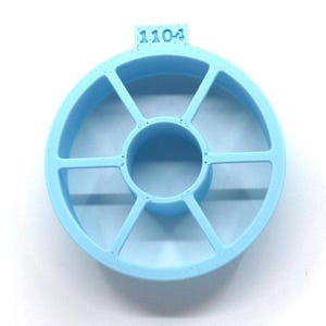May include: A light blue plastic spool holder with six compartments and a center hole. The holder has the number "1104" printed on the top.