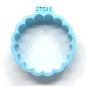 May include: Light blue plastic cookie cutter shaped like a circle with a scalloped edge. The cutter has the number "17011" embossed on the top.