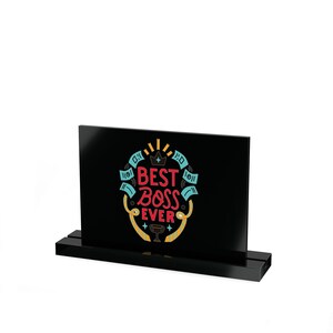 May include: A black desk sign with the words "BEST BOSS EVER" in red, blue, and yellow. The sign has a crown and trophy graphic. The sign is set in a black base.