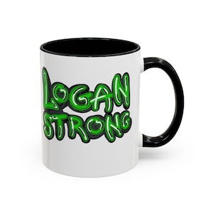 May include: White ceramic mug with a black interior and handle. The mug features the words "LOGAN STRONG" in green bubble letters with a black outline. The mug is designed for hot or cold beverages.
