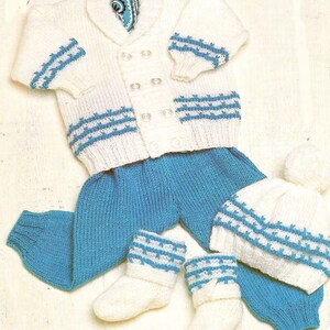 Puede incluir: Un conjunto de bebé tejido en blanco y azul. El conjunto incluye una rebeca cruzada con rayas azules, pantalones a juego, un gorro con pompón y calcetines. Una bufanda estampada está metida en la rebeca.