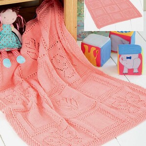 May include: A soft, pink knitted baby blanket with a square pattern featuring butterfly and leaf designs. The blanket is draped over a wooden nightstand, with a doll and colorful toy blocks in the background. The blanket is approximately 40 inches by 40 inches.