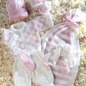 Könnte beinhalten: Eine Kollektion von Babykleidung und Accessoires in zartem Rosa und Weiß. Das Set beinhaltet eine Strickmütze mit Bommel, Babyschuhe, eine Strickjacke, einen Strampler, Fäustlinge und eine gestreifte Decke.