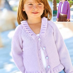 May include: A light purple knit cardigan featuring a V-neckline with a ruffled collar, long sleeves, and a button-down front with four light-colored buttons. The hem of the cardigan also features a matching ruffled knit trim detail.