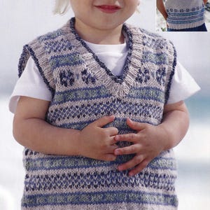 Può includere: Un gilet lavorato a maglia per bambini con scollo a V. Il gilet presenta un motivo a righe orizzontali e disegni geometrici blu, grigi e bianchi. Il bambino indossa anche una maglietta bianca sotto. Un capo comodo e fatto a mano.