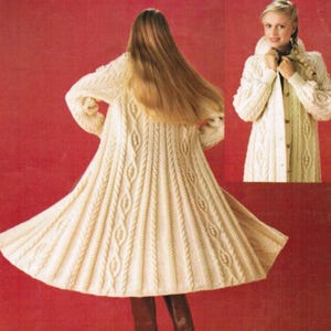 May include: Cream-colored, long knitted coat with a flared skirt and cable knit detailing. The coat features a button-up front and a high collar. The image shows the coat from the back and a side view, set against a red background.
