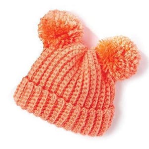May include: A coral-colored knitted hat with two large, fluffy orange pom-poms. The hat features a ribbed knit design and is made of a soft, warm material. This winter hat is perfect for keeping warm in cold weather.