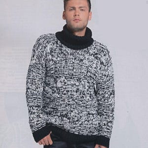 May include: A black and white knit sweater with a high, black turtleneck. The sweater has a textured pattern and ribbed cuffs and hem. The model is wearing black pants.