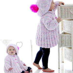 May include: Two children's knitted outfits. The outfits are light pink with flecks of color and feature a hooded coat with a bright pink pom-pom and matching hat. One child is standing and the other is sitting. Both are wearing dark blue leggings.