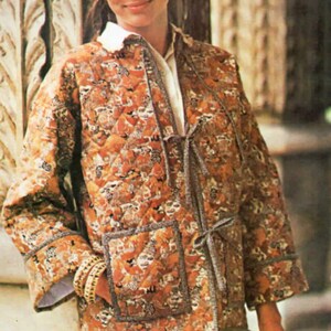 Könnte beinhalten: Gesteppte Jacke mit braunem und orangefarbenem Blumenmuster. Die Jacke hat einen Bindverschluss, zwei Vordertaschen und einen weißen Kragen. Die Ärmel sind umgeschlagen, und die Jacke wird über einem weißen Hemd getragen.