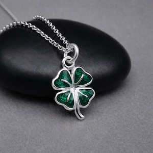 May include: A silver necklace featuring a four-leaf clover pendant. The clover has a vibrant green enamel finish with silver detailing. The chain is a delicate silver link style, perfect for everyday wear.