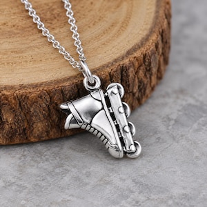 May include: A silver-toned necklace featuring a pendant shaped like an inline skate. The pendant displays detailed molded features including the boot structure and a frame with four wheels. The piece hangs from a delicate silver-toned chain link.