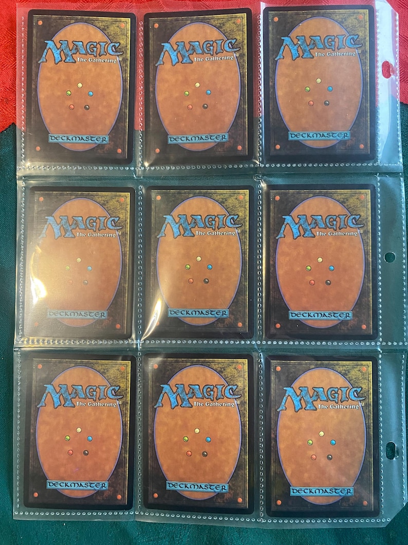 May include: Nine Magic: The Gathering cards in a clear plastic page protector. The cards are all black and red with gold accents and feature the Magic: The Gathering logo.