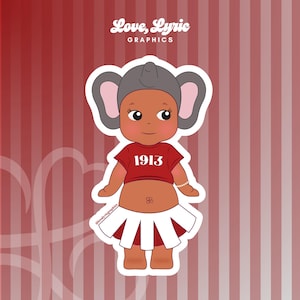 May include: A sticker featuring a cartoon character with an elephant ear hat, red shirt with "1913" text, and a white and red skirt. The sticker has the text "Love, Lyric Graphics" in the upper left corner.