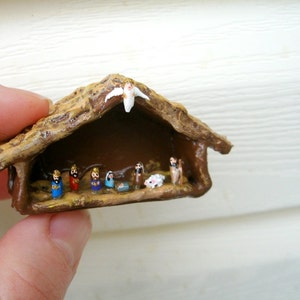 May include: A miniature nativity scene, featuring a rustic, thatched-roof stable. Inside, tiny figurines depict the holy family and the three wise men. The scene is painted with vibrant colors and detailed craftsmanship, perfect for holiday decor.