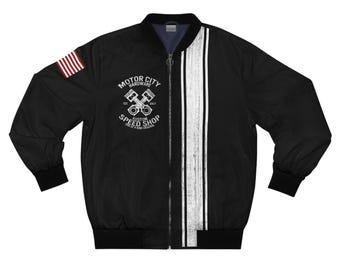 May include: Black bomber jacket with a white stripe down the front and an American flag patch on the left sleeve. The jacket features the text "MOTOR CITY HARDWARE CUSTOM SPEED SHOP" and a graphic of crossed pistons.