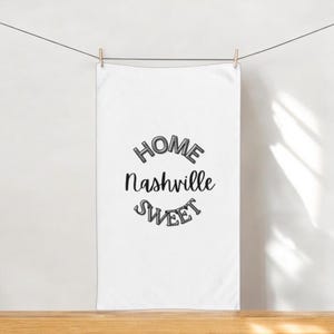 Puede incluir: Toalla de cocina blanca con el texto "Home Sweet Nashville" en letras negras y grises.