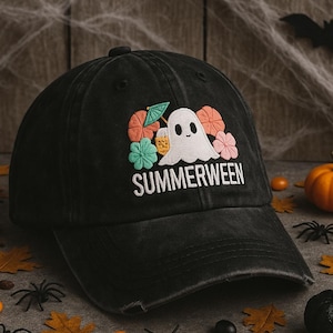 May include: Black distressed baseball cap with the word "SUMMERWEEN" embroidered in white. The cap features a ghost graphic with colorful floral and drink accents. The background includes Halloween decorations like spiders, pumpkins, and leaves.