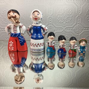 Peut inclure: Ensemble de figurines en céramique peintes à la main, représentant des personnages folkloriques ukrainiens. Les figurines arborent des vêtements traditionnels rouges, blancs, bleus et noirs, ornés de motifs floraux et géométriques. La plus grande mesure environ 20 cm.
