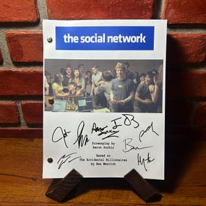 Puede incluir: Un guion blanco con el título "the social network" en texto azul. El guion está firmado por Aaron Sorkin, Ben Mezrich y otros. El guion está basado en el libro "The Accidental Billionaires" de Ben Mezrich.