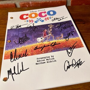 May include: A signed Disney Pixar Coco movie script. The cover features the movie title in colorful letters and an illustration of characters. The script is signed by several people in black ink. The screenplay is by Adrian Molina and Matthew Aldrich.