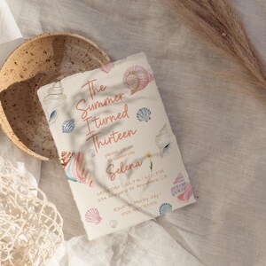 Pu&ograve; includere: Un invito di compleanno a tema conchiglie. Il testo recita "The Summer I Turned Thirteen" in corsivo rosa, con ulteriori dettagli in basso. Illustrazioni di conchiglie rosa, blu e bianche decorano l'invito. Una ciotola beige e una borsa a rete sono sullo sfondo.