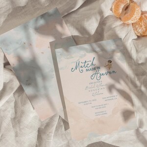 May include: Bridal shower invitations with a watercolor design in soft pastel colors. The text "Match Made in Heaven" is displayed in elegant script, along with event details. Two orange mandarin orange slices are in the upper right corner.