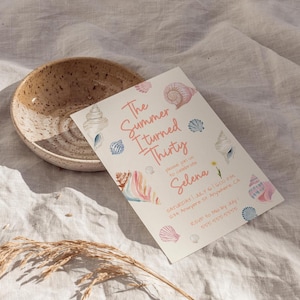 Puede incluir: Una invitaci&oacute;n de cumplea&ntilde;os con ilustraciones de conchas marinas y el texto "The Summer I Turned Thirty" en rosa. La invitaci&oacute;n incluye detalles de la fiesta, con un cuenco de cer&aacute;mica moteada en el fondo.