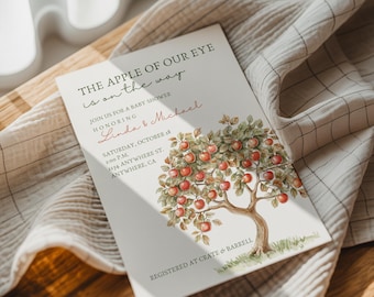 Peut inclure: Invitation de baby shower avec le texte "The Apple of Our Eye is on the way". L'invitation présente une illustration d'un pommier avec des pommes rouges. Les noms "Linda & Michael" sont en écriture cursive.