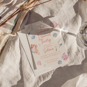 Puede incluir: Dos tarjetas de invitaci&oacute;n blancas con ilustraciones de conchas marinas y el texto "The Summer I Turned Thirty" en rosa. La invitaci&oacute;n incluye el nombre "Selena" y los detalles del evento.