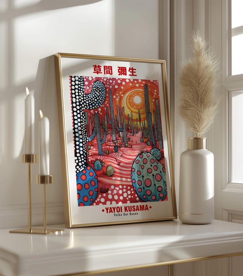 May include: A framed art print featuring a desert landscape with cacti and a sun, in a style reminiscent of Yayoi Kusama. The artwork uses red, blue, and white polka dots. The text "YAYOI KUSAMA Polka Dot Queen" is visible.