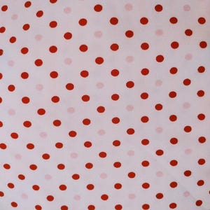 May include: Close-up of a white fabric with a repeating pattern of red polka dots. The dots are evenly spaced and vary slightly in size, creating a playful and classic design. The fabric appears to be soft and lightweight.
