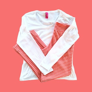 May include: A white long-sleeved shirt with a v-neck and a pair of coral striped leggings.
