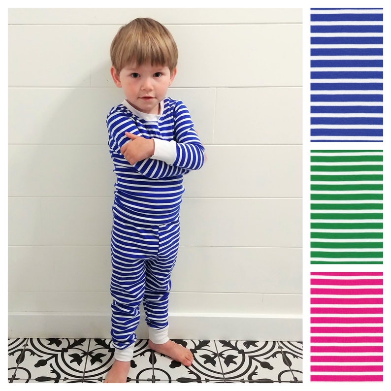 以下が含まれることがあります： 青と白のストライプのパジャマを着た幼い子供。パジャマは長袖のシャツと長いズボンです。