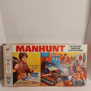 May include: A vintage "Manhunt" board game box. The box features illustrations of children and adults using a computer to solve a mystery. The game is described as "The Electric Computer Detective Game". The box is yellow, red, and blue.