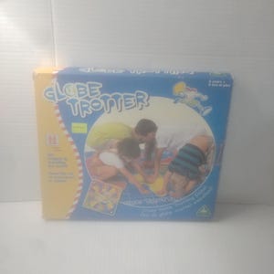 May include: A boxed board game titled "Globe Trotter" with a blue and yellow design. The box features illustrations of children playing the game. Text on the box includes "Crazy Globe Trotting Game" and "4 years & up."