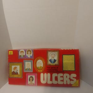 May include: A red game box with the title "ULCERS" in large white letters. The game is described as "The game of manipulating company personnel". The box features illustrations of people in framed portraits.