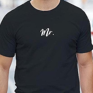 以下が含まれることがあります： 白い筆記体で「Mr.」と書かれた黒いクルーネックTシャツ。 シャツは無地で半袖です。 Tシャツは柔らかい素材で作られています。