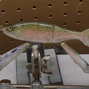 May include: A white ceramic mug with a black handle and the text "But First, Coffee" in a bold, black font. The mug is set against a blurred background, suggesting a cozy setting.
