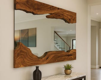 May include: Large rectangular mirror with a natural wood frame. The frame has a unique, organic edge. The mirror hangs above a marble-topped console table. A dark vase and a small potted plant sit on the table.