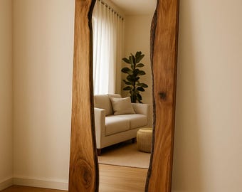 May include: Full-length mirror with a rectangular reflective surface framed by two thick, natural-edge wooden planks. The wood has a warm, brown tone with visible grain and knots. The mirror reflects a room with a sofa, plants, and a neutral colour palette.