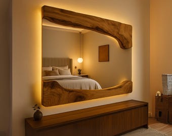 May include: A large, rectangular mirror with a unique, natural wood frame. The frame has an organic shape and is illuminated with warm, yellow lighting. The mirror reflects a bedroom scene.