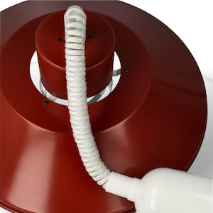 Puede incluir: Lámpara de escritorio moderna, roja, con pantalla circular y base cilíndrica. Cuenta con un cable blanco en espiral y un conector de alimentación cilíndrico blanco. El diseño es minimalista y funcional.