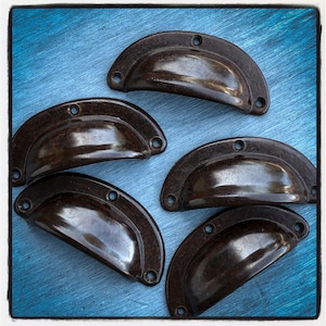 May include: Five antique brown cabinet pulls with a rounded, half-circle shape. The pulls are made of a shiny, dark brown material and have a smooth, polished finish.