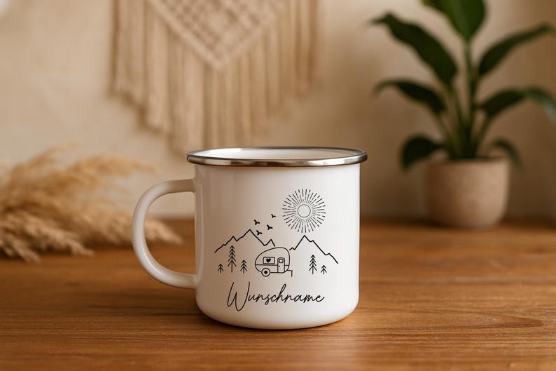 May include: White enamel camping mug with a black illustration of mountains, a sun, birds, and a camper. The mug has a silver rim and a curved handle. The word "Wunschname" is written in a script font on the mug.