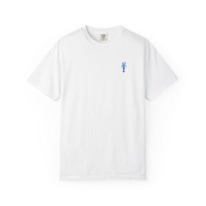 Könnte beinhalten: Weißes T-Shirt mit einer kleinen blauen Hummerstickerei auf der Brust. Das Shirt hat kurze Ärmel und einen Rundhalsausschnitt. Der Stoff scheint eine weiche Baumwollmischung zu sein, die sich für Freizeitkleidung eignet. Das Design ist schlicht und minimalistisch.