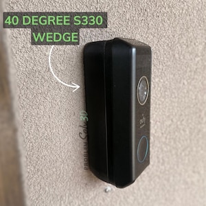 Könnte beinhalten: Ein schwarzer eufy Sicherheits-Türklingel-Keil an einer strukturierten beigefarbenen Wand. Der Text "40 Degree S330 Wedge" befindet sich in einem grünen Feld über der Türklingel. Die Türklingel hat ein Kameraobjektiv und einen blauen Lichtring.