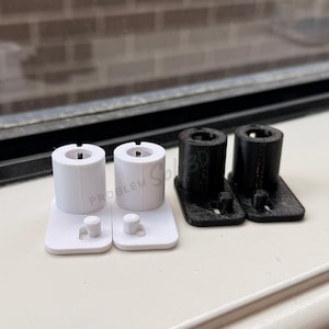 May include: Two pairs of 3D-printed plastic components. One pair is white, the other is black. Each component has a cylindrical top and a rectangular base. The text "PROBLEM SOLVED" is visible on the white components.