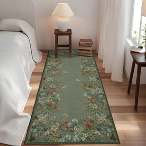 Peut inclure: Un tapis de couloir floral vert avec un fond vert clair et une bordure de fleurs blanches, orange et vertes. Le tapis est plac&eacute; sur un sol en bois dans une pi&egrave;ce avec un lit blanc et une table d'appoint avec une lampe.